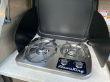 A compact, stainless steel Flame King two-burner gas stove with its cover open, found in an RV rental kitchen.