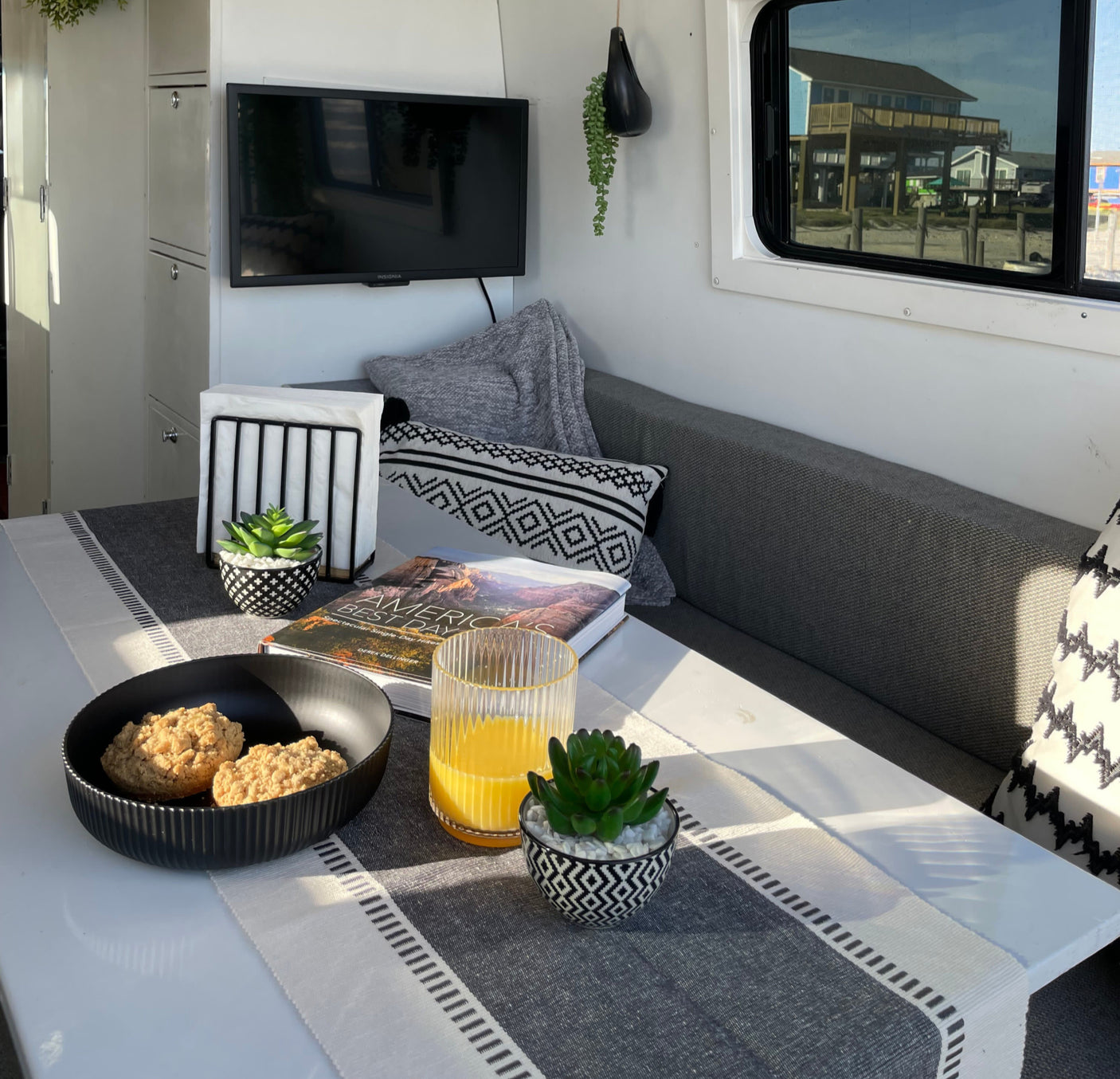 Cozy RV rental interior with breakfast on the table, offering a scenic beach house view.