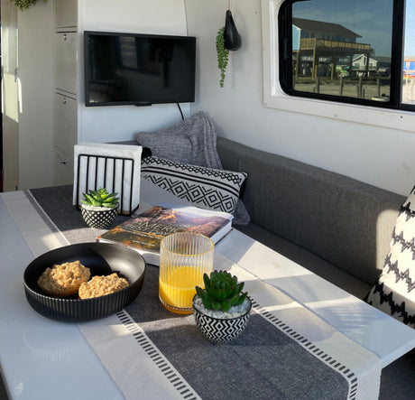 Cozy RV rental interior with breakfast on the table, offering a scenic beach house view.