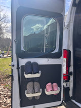 RV rental storage: Pink, blue, and grey clogs secured on a door panel. Efficient shoe organization for camper travel.