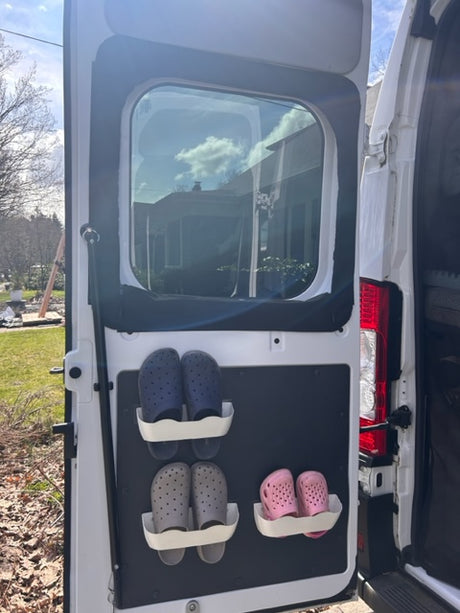 RV rental storage: Pink, blue, and grey clogs secured on a door panel. Efficient shoe organization for camper travel.