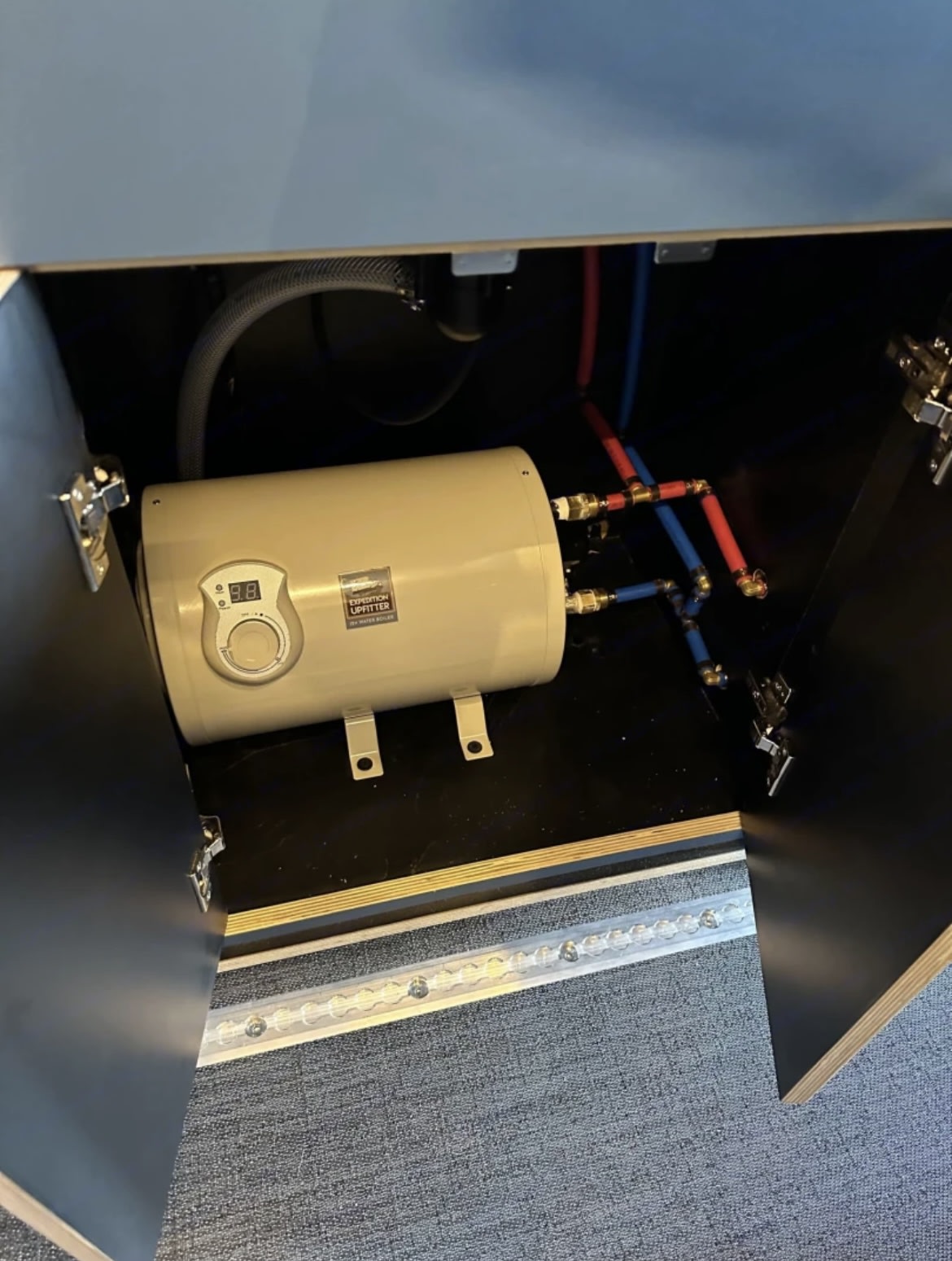  and overhead stowed bed. Perfect for mobile living.|Compact under-seat heater unit in an RV rental van. White housing with a front vent provides comfort.|Stainless steel Contoure microwave with digital controls — photo 11