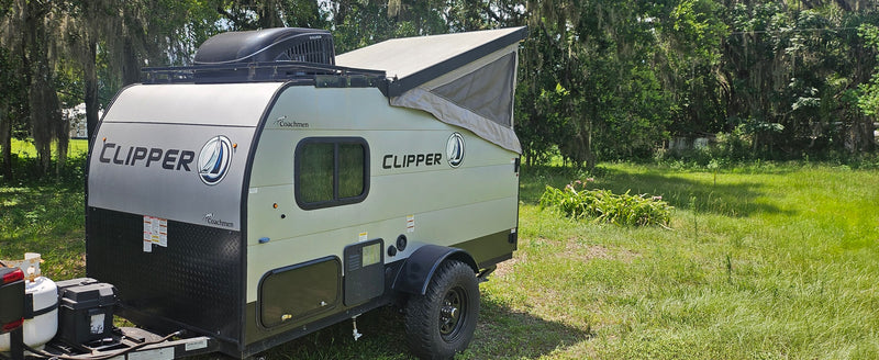 A compact Coachmen Clipper pop-top travel trailer, ready for your rv rental adventure, parked in a green, wooded area. — photo 3