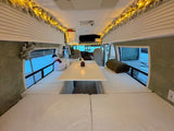 Cozy winter RV rental interior with festive garland lights, a snowman, and comfy seating. Perfect for snowy escapes.