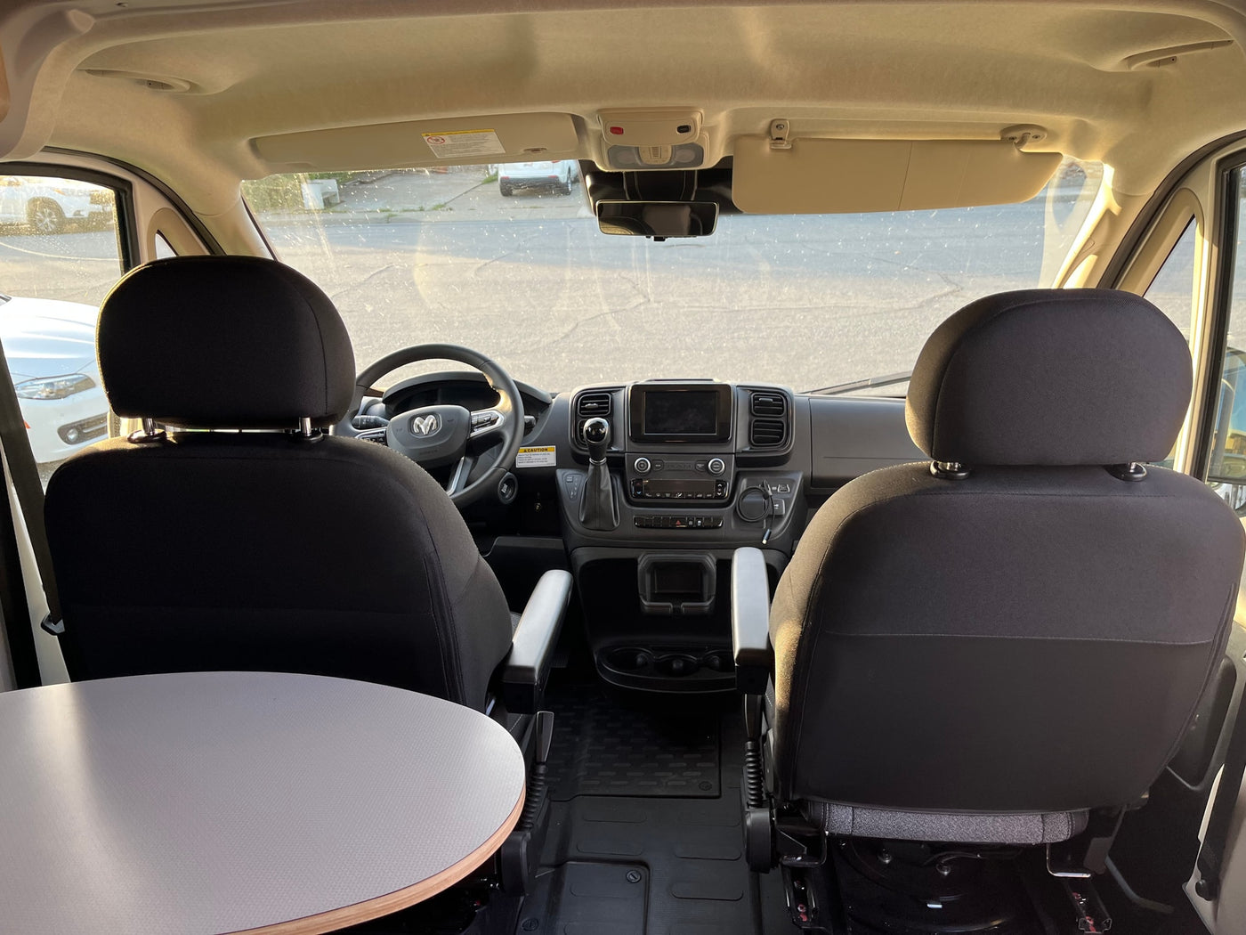 Inside an RV rental camper van: view of the dashboard, front seats, and a swiveling table on the left. — photo 7