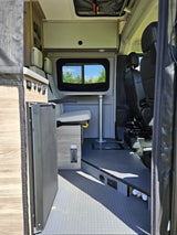RV rental camper van interior: compact kitchen, dinette with table, front seats, and overhead storage.