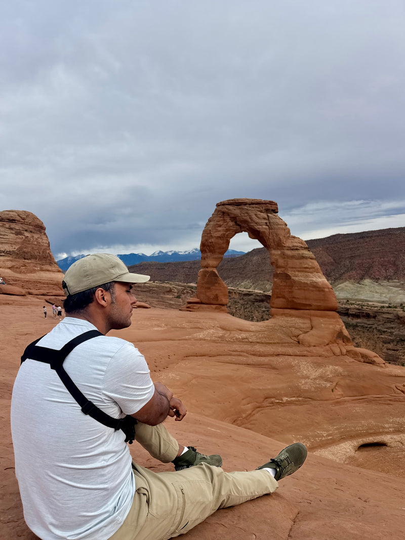 Stunning views of Delicate Arch from Arches National Park. A man sits, taking in the red rock landscape—perfect for an RV rental trip. — photo 18