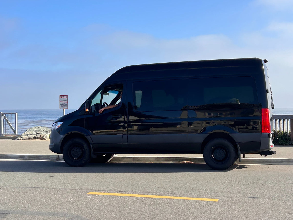 Black RV rental van parked oceanside