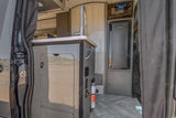 Compact rv rental kitchen with a sink, microwave, fridge, and fire extinguisher in a modern van interior.