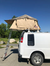 White RV rental van with a beige rooftop tent deployed, ladder extended. Perfect for van life and camping adventures.