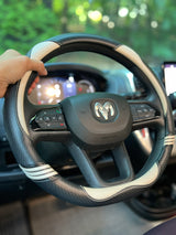 A hand holds a black and white steering wheel cover with a Ram logo, inside an RV rental, ready for travel.