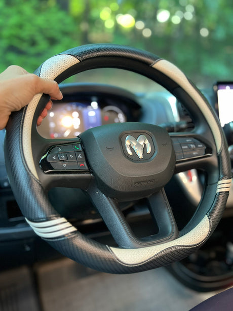 A hand holds a black and white steering wheel cover with a Ram logo, inside an RV rental, ready for travel.