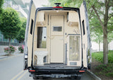 Rear view of an RV rental camper van with open doors, revealing a compact interior with a toilet, sink, and kitchen.