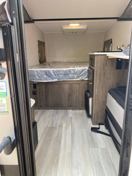 Inside a cozy rv rental with a bed, kitchenette, and wood finishes, ideal for compact travel.