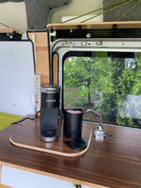 Compact coffee station in an RV rental, featuring a Keurig on a wooden counter with a view of trees. Perfect for mobile living.