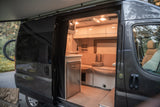 Explore this modern RV rental's inviting interior. It features a kitchen, comfortable seating, and an extended awning, ready for adventure.