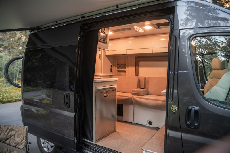 Explore this modern RV rental's inviting interior. It features a kitchen, comfortable seating, and an extended awning, ready for adventure. — photo 8