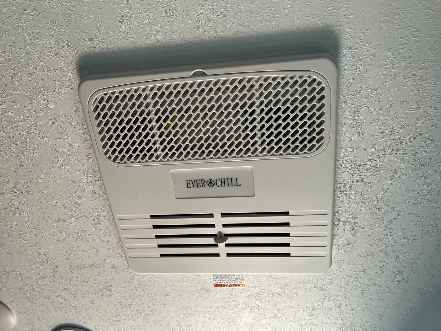 RV rental overhead: EVERCHILL air conditioner vent on ceiling, with a visible warning label.