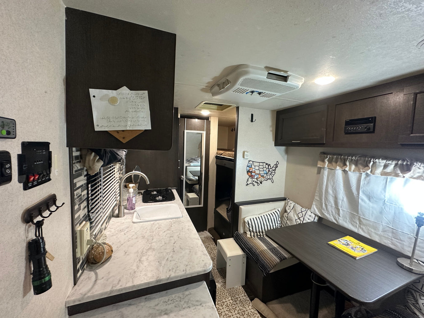 This RV rental interior features a compact kitchen, dining area, and bunk beds. Cozy space for travel adventures.