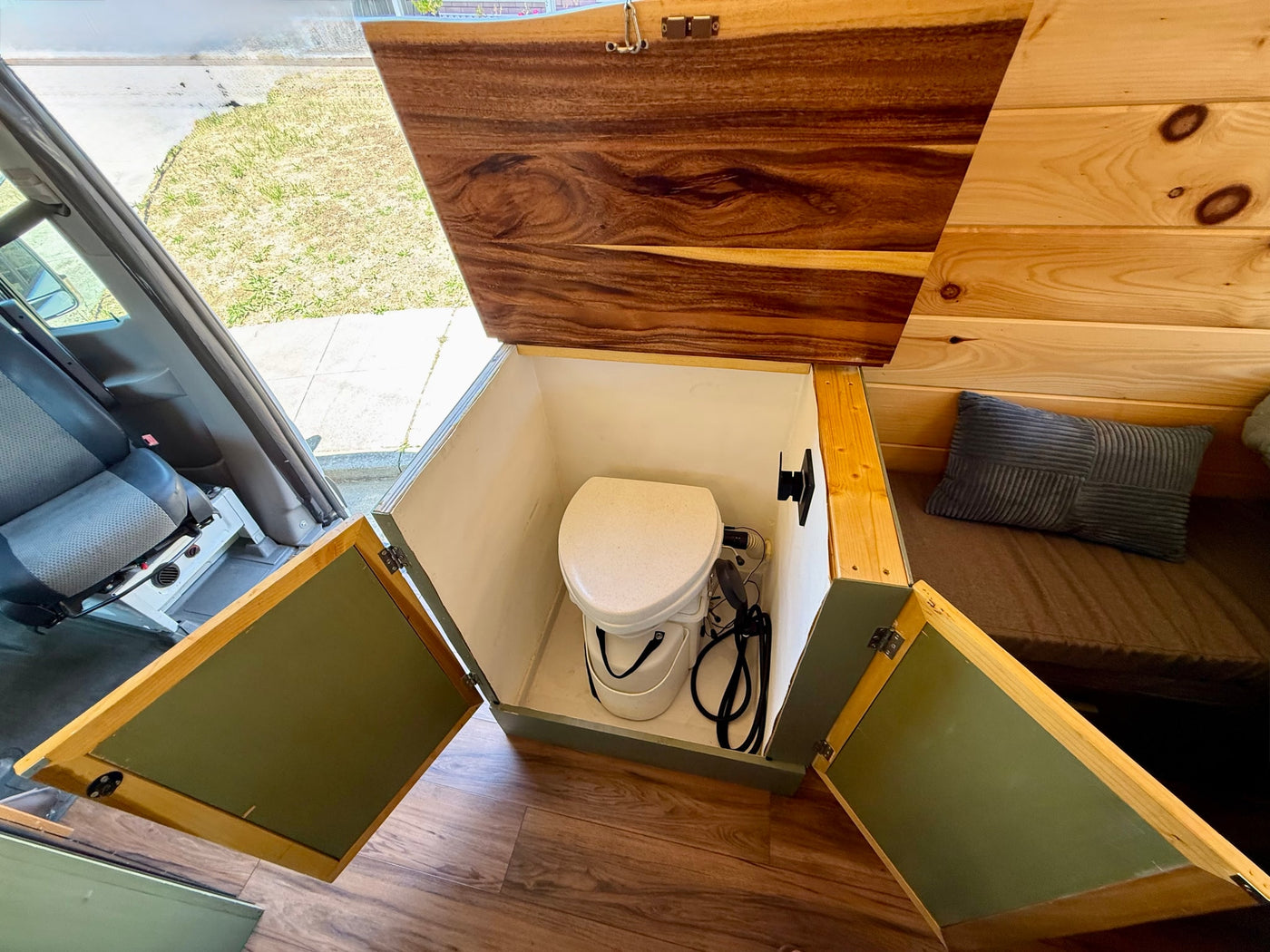 RV rental interior: cleverly stored portable toilet in a custom wood cabinet with a lift-top lid and hinged doors. — photo 17
