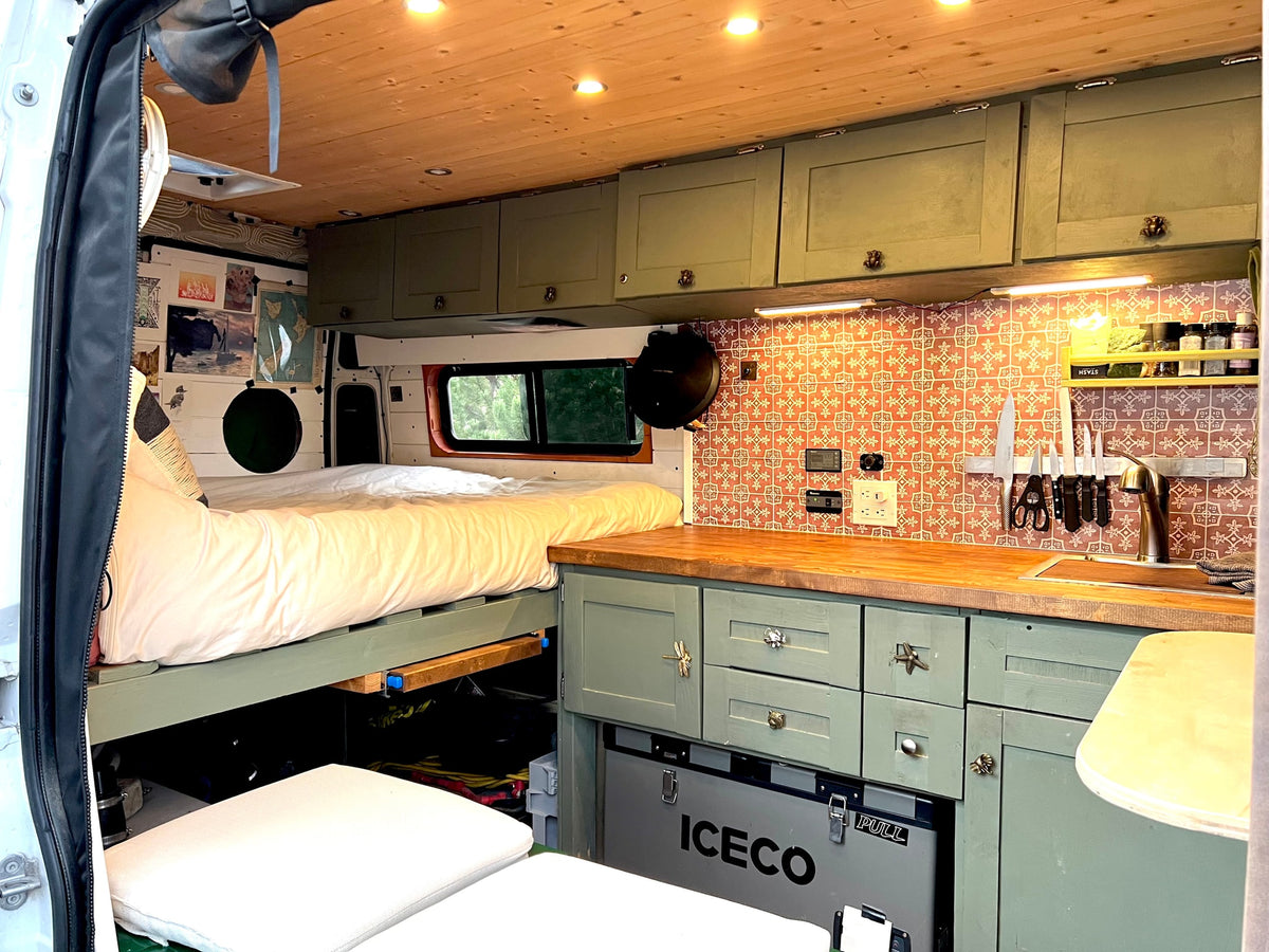 RV rental: A stylish camper van interior featuring a comfortable bed, full kitchen, and smart storage solutions. — photo 5