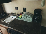 Compact RV rental kitchen: sink, stovetop, coffee maker, and fresh towels for home-like comfort on the road.
