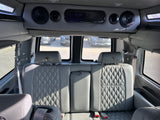 Luxury RV rental: detailed view of plush, grey quilted rear seats with globe emblems & overhead console with speakers.