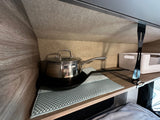Compact RV rental kitchen storage with a pot, pan, and non-slip mat. Ideal for camper cooking essentials.