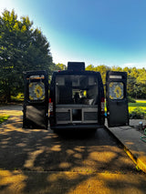 Open for adventure: a custom black camper van interior (potential rv rental) with unique sunflower window covers, parked on a sunny day.