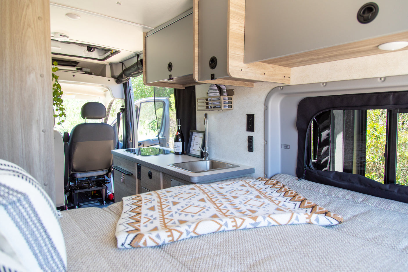 Step inside this rv rental's well-equipped interior, featuring a compact kitchen with sink/stovetop, comfy bed, and ample storage.