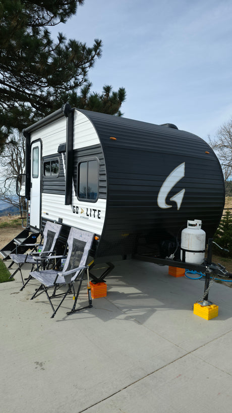 Enjoy outdoor comfort with this stylish Go Lite rv rental, featuring a black and white travel trailer and camping chairs.