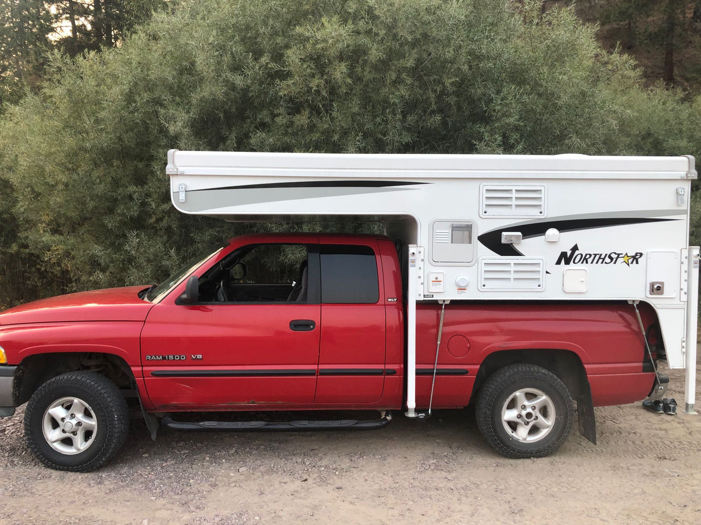  parked on dirt. Ideal RV rental for off-grid adventures.|Red Dodge truck with Northstar truck camper by a river. Perfect for an RV rental adventure in Montana!|RV rental TC 650 floor plan: Compact camper interior with kitchen (stove — photo 2