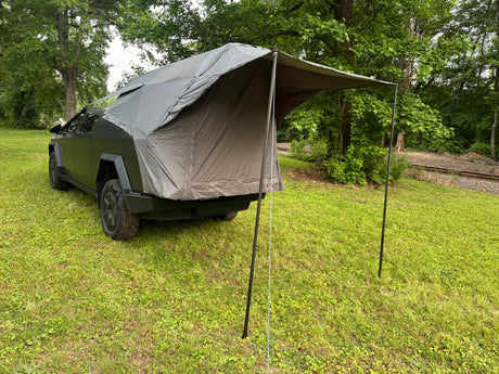  perfect for an rv rental adventure in nature.|Dark grey Tesla Cybertruck with an attached rear tent