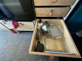 Efficient RV rental kitchen storage with pull-out drawers, showing various cooking essentials and glass containers.