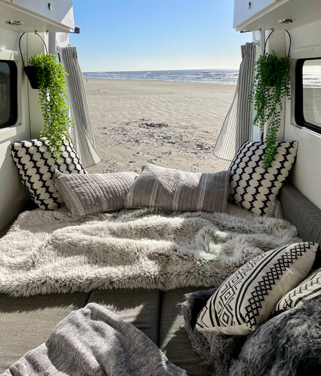 Cozy RV rental setup with plush pillows and blankets, offering a beautiful beach and ocean view for ultimate relaxation.