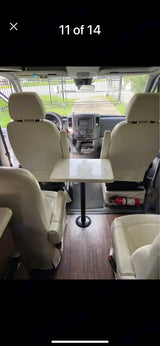 RV rental interior showcasing front swivel seats, a central table, and rear seating for a cozy dinette. Fire extinguisher visible.