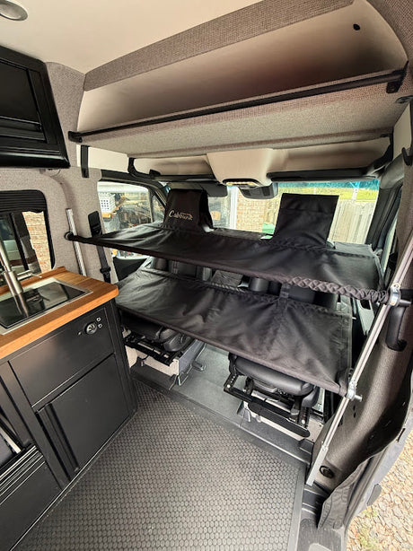 Inside this RV rental: a practical camper van interior with a sleek kitchen, swivel front seats, and space-saving Cabbunk beds.