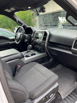 Modern Ford truck interior: dashboard, steering wheel, cloth seats. Consider this comfortable ride for your next RV rental adventure.