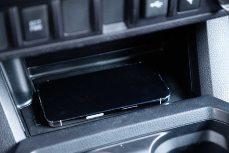 A smartphone rests in an RV rental's console charging tray, ready for your road trip adventures.