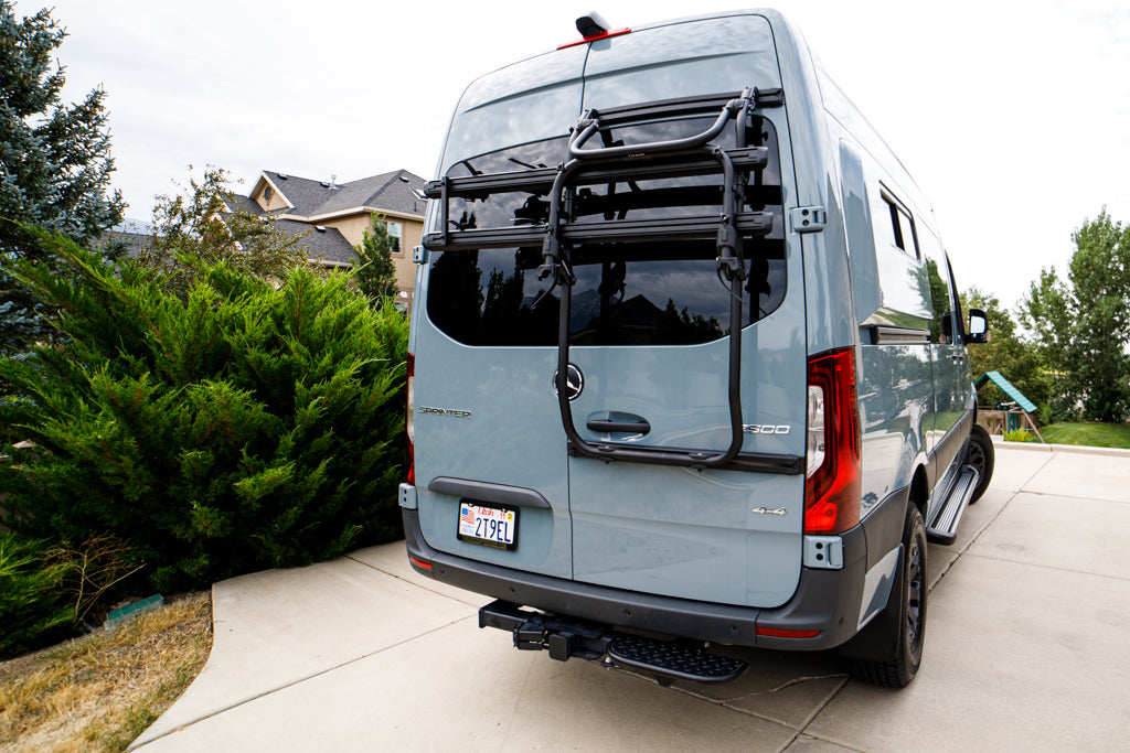 Rear view of a grey Mercedes Sprinter 4x4 RV rental, equipped with a bike rack & step.