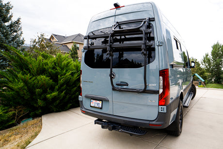 Rear view of a grey Mercedes Sprinter 4x4 RV rental, equipped with a bike rack & step.