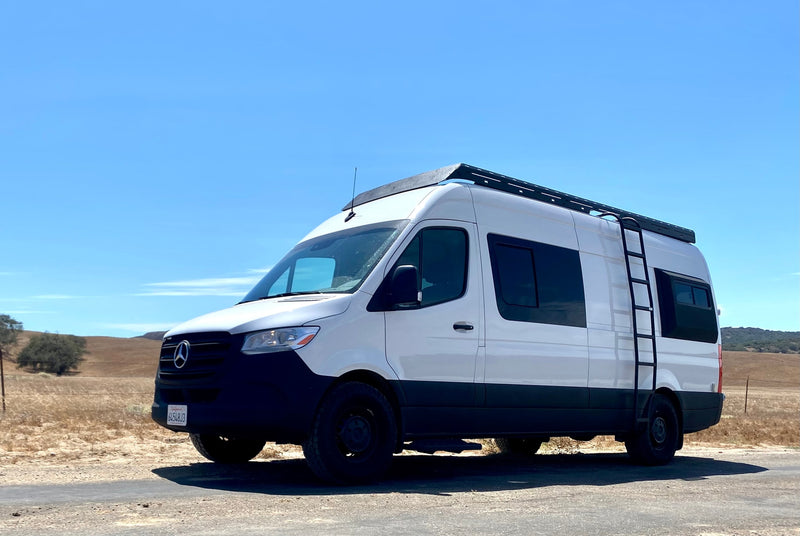 White Mercedes-Benz Sprinter RV rental on a dirt road in a dry, hilly landscape under a blue sky, ready for adventure. — photo 9