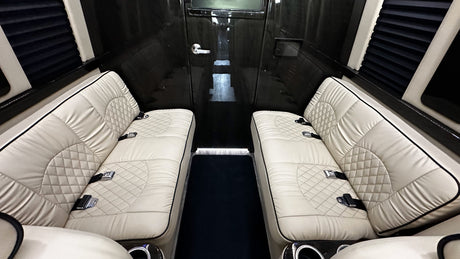 Luxurious RV rental interior with opposing cream quilted seats, dark paneling, and privacy blinds. Ideal for comfortable travel.