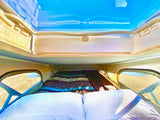 Inside an RV rental: a comfortable bed under a clear pop-top roof, offering sky views. Ready for adventure.