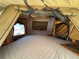 Spacious camping tent interior: quilted sleeping pad, window view, and storage pockets. Great for **RV rental** adventures.