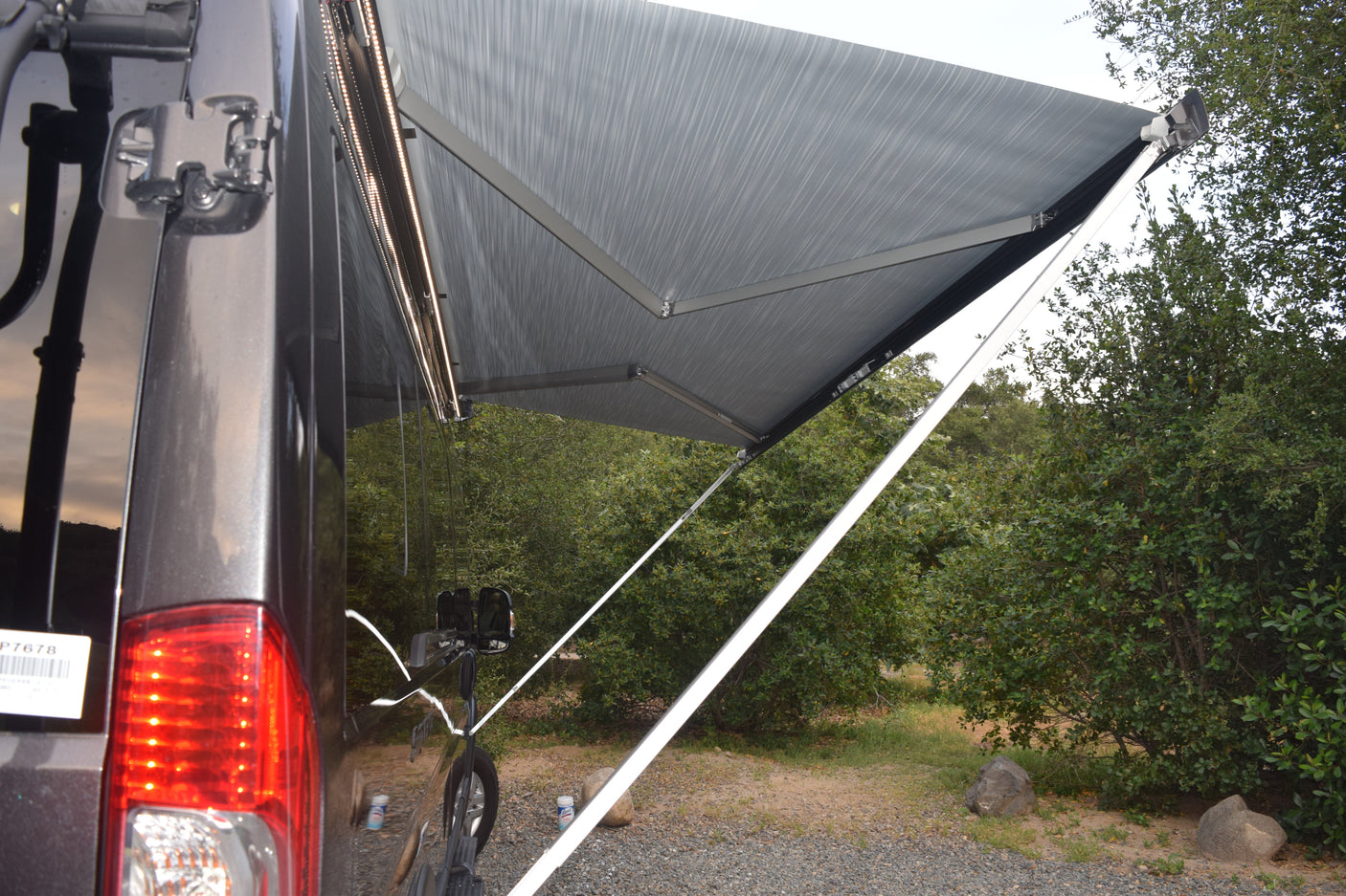 An RV rental with its grey awning extended, featuring bright LED lights for enhanced outdoor living.