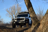 Adventure-ready white Jeep Rubicon with a rooftop tent, perfect for an RV rental escape, parked on a dirt path.