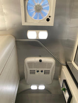 Inside an RV rental, a metallic ceiling with a MaxxAir fan, Dometic AC unit, and bright LED lights provides comfort.