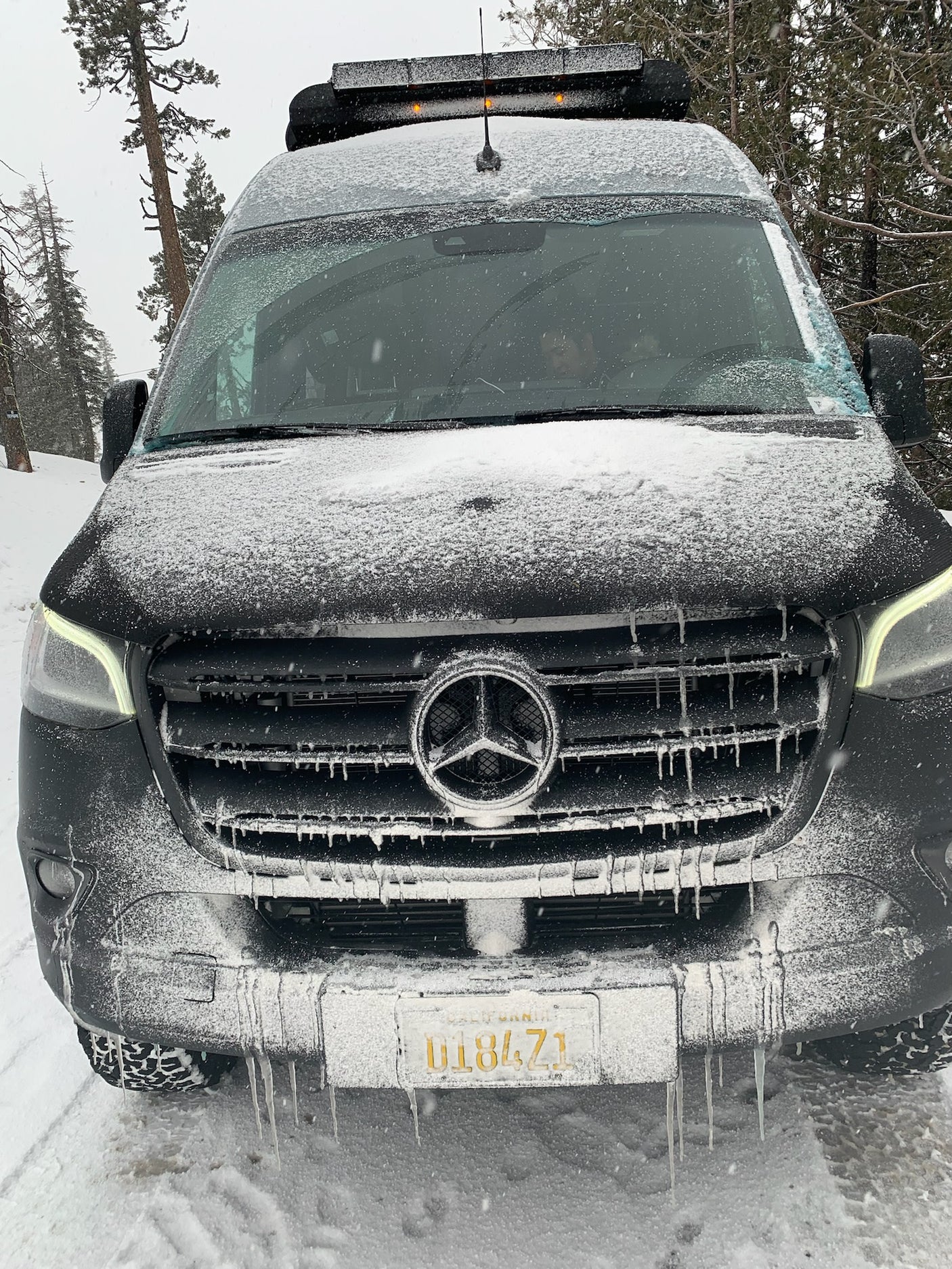 This snowy Mercedes Sprinter van, an RV rental, is covered in icicles. Ready for winter adventure!
