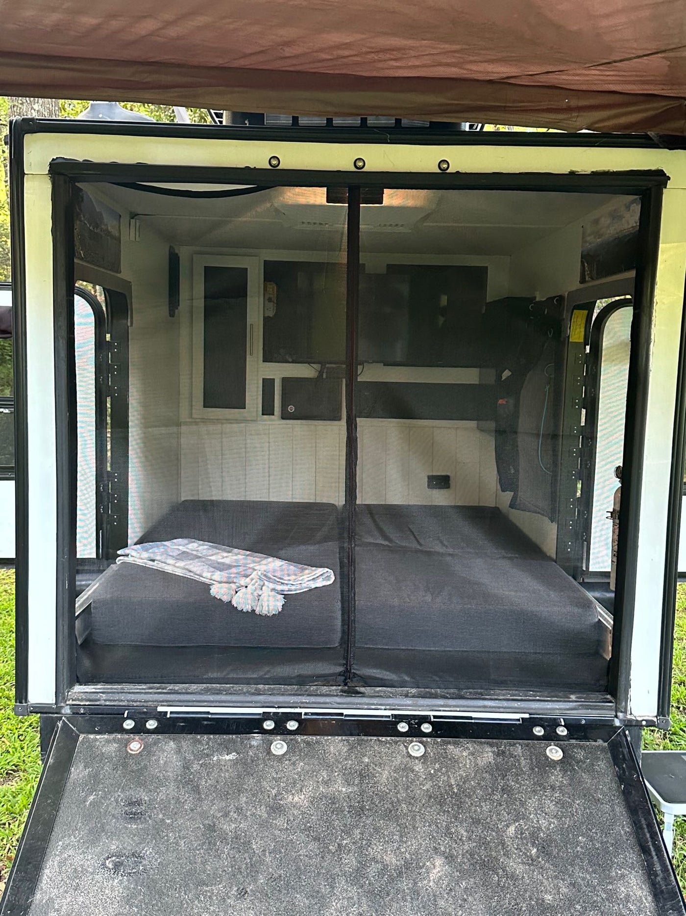 Rear view inside an RV rental shows a comfy bed, mesh screen door, and built-in storage for travel & camping. — photo 8
